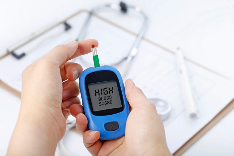 hand holding blood glucose meter measuring blood sugar background is stethoscope chart file 1