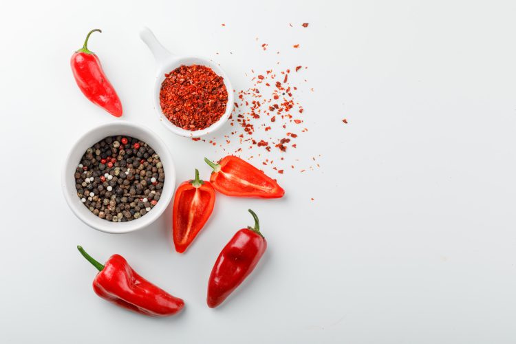 peppercorns with chili powder scoop red peppers plate white wall top view