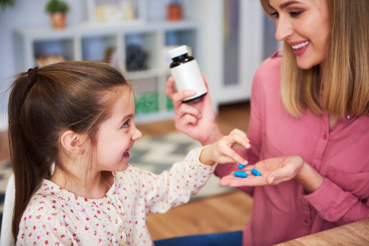 young mum giving her little daughter medicine