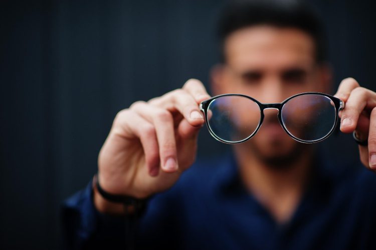 middle eastern entrepreneur wear blue shirt show close up eyeglasses against steel wall